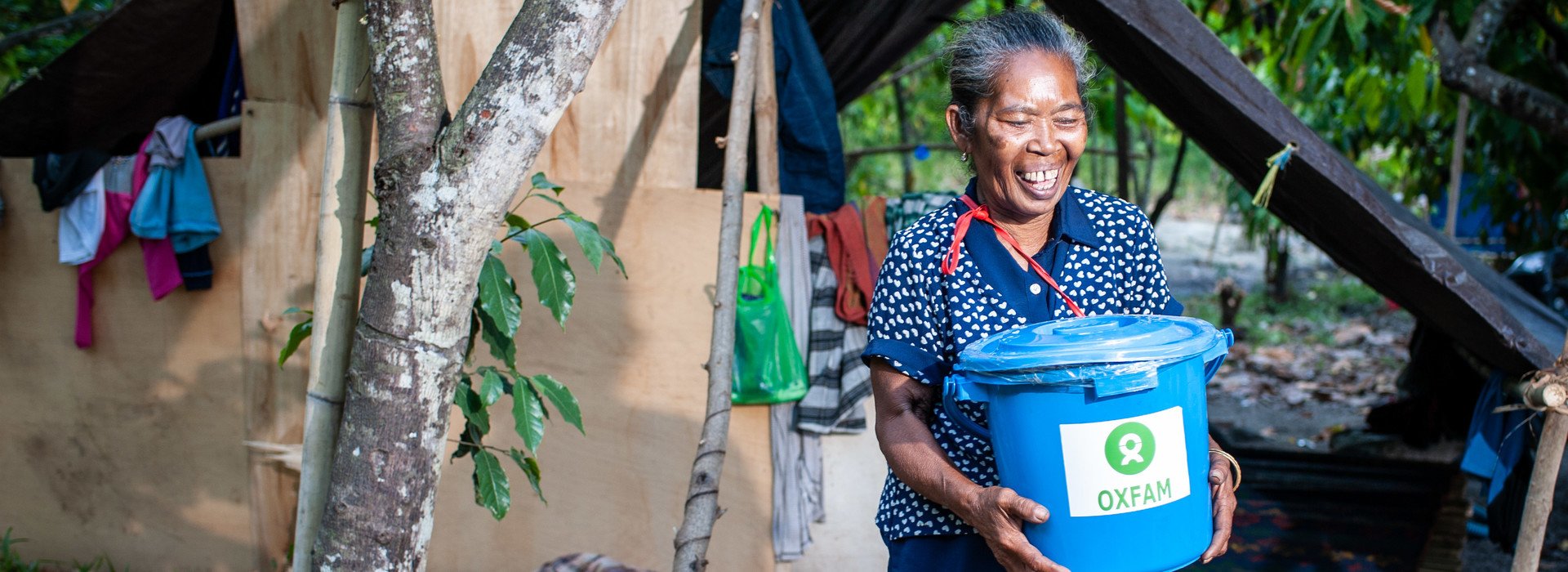 在印尼中部帕卢的近郊地区Dolo Seletan，一名62岁的妇女取得个人卫生套装，储水桶内有毛巾、牙膏、牙刷、肥皂等日用品，让灾民保持个人卫生。（图片：Hariandi Hafid/澳洲乐施会）